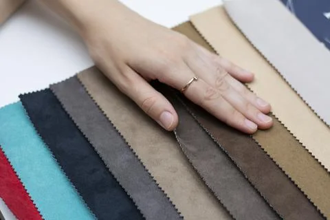Samples of artificial suede. Women's hands on sheets of suede fabric close-up. Stock Photos