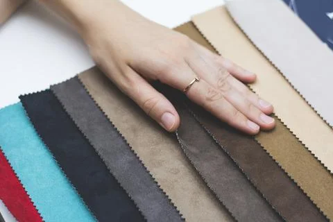 Samples of artificial suede. Women's hands on sheets of suede fabric close-up. Stock Photos