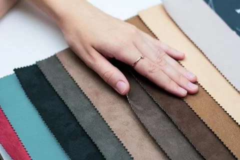 Samples of artificial suede. Women's hands on sheets of suede fabric close-up. Stock Photos