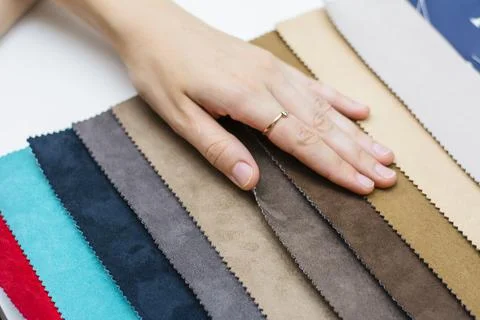 Samples of artificial suede. Women's hands on sheets of suede fabric close-up. Stock Photos
