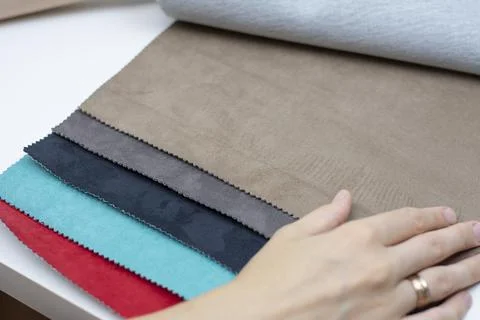 Samples of artificial suede. Women's hands on sheets of suede fabric close-up. Stock Photos