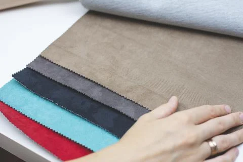 Samples of artificial suede. Women's hands on sheets of suede fabric close-up. Stock Photos