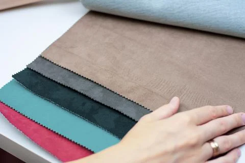 Samples of artificial suede. Women's hands on sheets of suede fabric close-up. Stock Photos