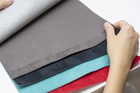 Samples of artificial suede. Women's hands on sheets of suede fabric close-up. Stock Photos