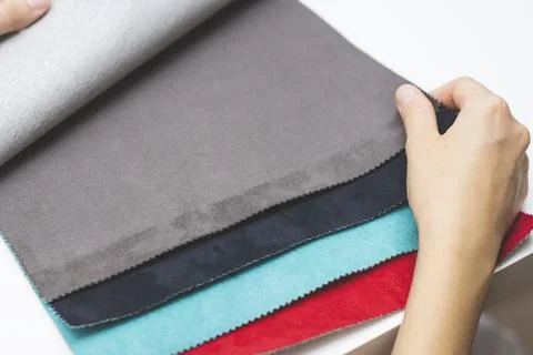 Samples of artificial suede. Women's hands on sheets of suede fabric close-up. Stock Photos