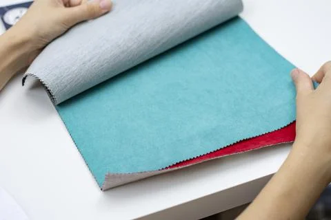 Samples of artificial suede. Women's hands on sheets of suede fabric close-up. Stock Photos