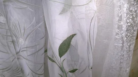 Samples of different types of white luxury tulle. Embroidery of green leaves. Stock Photos