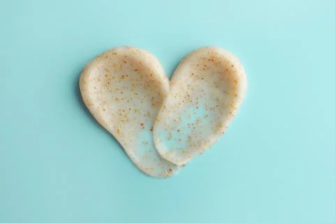 Samples of face scrub in shape of heart on light blue background, top view Stock Photos
