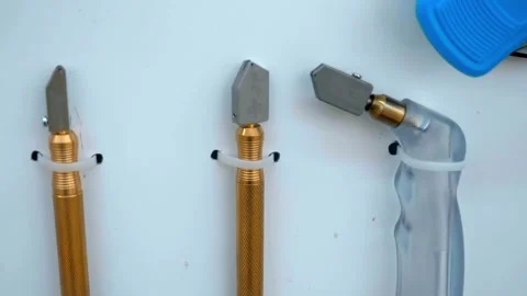 Samples of hand-held glass cutters hang on a white wall Stock Footage 333393470