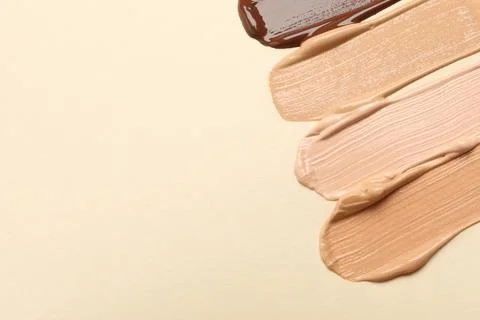 Samples of skin foundation on beige background, flat lay. Space for text Stock Photos