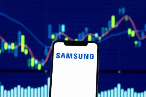 Samsung logo is seen on an android mobile phone over stock chart Stock Photos