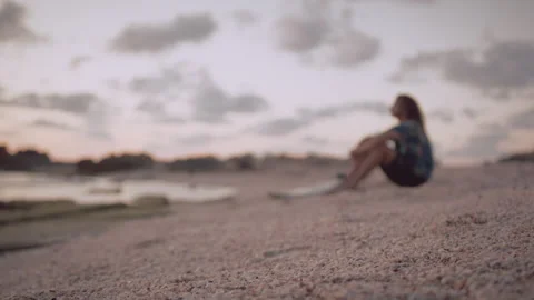 Sand and shells on the beach at sunset by a man sitting and looking out at .. Stock Footage 275157477