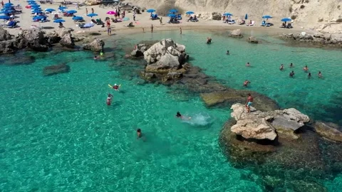 Sand and stone Beach with crystal blue water from drone. Jumping and swiming Stock Footage 153473307