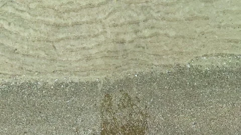 Sand and water blend at a beach shoreline during the day, showing textures and Stock Footage 339475261