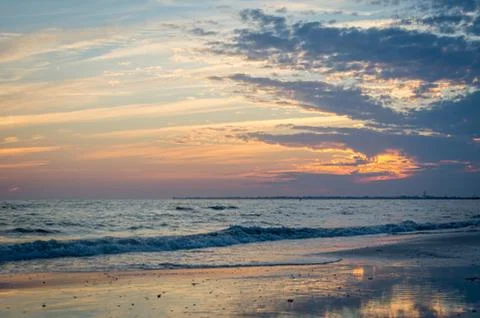 Sand and Waves on a Beach Durring Sunset Stock Photos