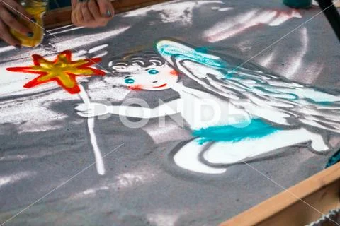 Sand animation, drawing sand closeup, girl drawing an angel on the sand Stock Photos