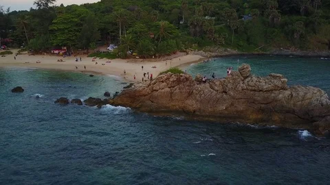 Sand bar connecting beach with rock in water, people walk and climb around Video stock 77696466