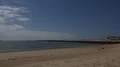 Sand beach and sea clouds timelapse people running to lighthouse pier Portugal 4k or 4k+ Resolution