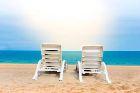 Sand beach with coconut trees with two chairs and bokeh beach tropical backgr Stock Photos
