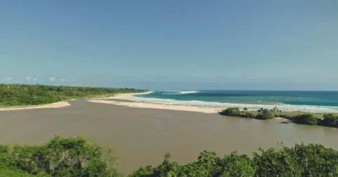 Sand beach at ocean bay waves with green leaves of exotic trees. Tropical coast Stock-Fotos