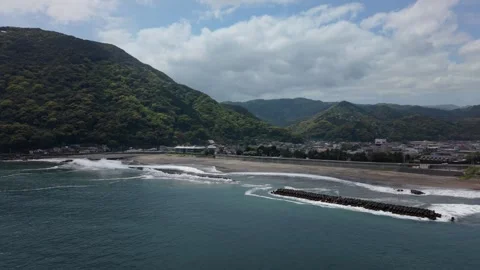 Sand beach with tetrapod breakwaters below a rounded green mountain, Kawazu 库存影片 345184425