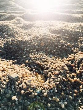 Sand beach texture background with rays of the sun. Detail of the grains of c Stock Photos