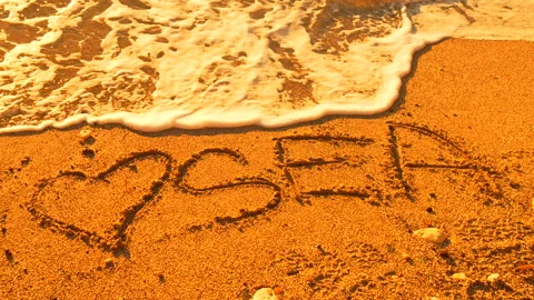 Sand beach wave erasing "LOVE SEA" message on golden shore Stock Footage 312985518