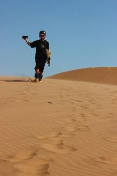 Sand boarder filming himself while walking over a dune in namibian desert Stock Photos