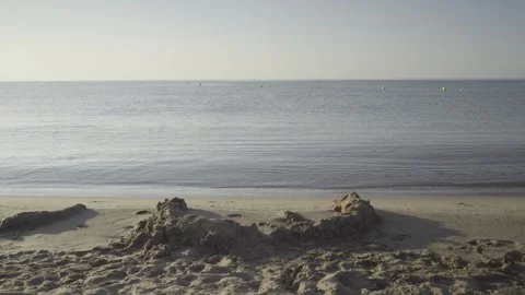 Sand castle on an empty beach against calm sea water horizon Stock Footage 342445991