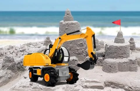 Sand castle under construction with yellow toy execavator Stock Photos