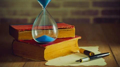 Sand clock with old books. Stock Photos