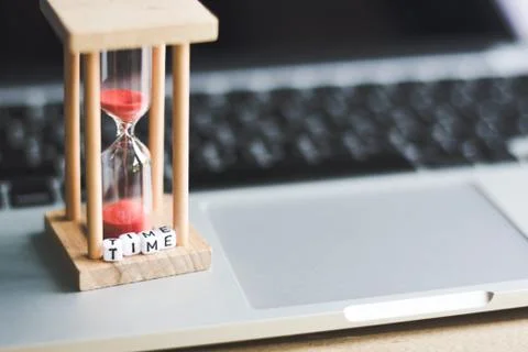 Sand clock timer on laptop with "TIME" alphabet cube letter .symbol of time Foto stock