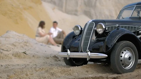 Sand desert at sunset. In the foreground is a black retro car. In the background Stock Footage 124258991