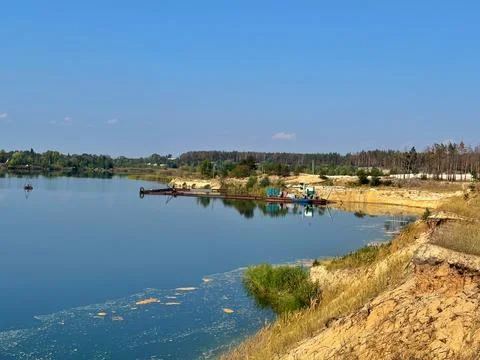 Sand Dredging Boat Operating in Quarry Lake near Forest Shore Stock Photos