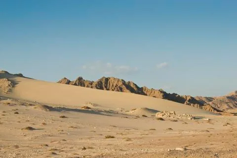 Sand dune with mountains in the background. Stock Photos