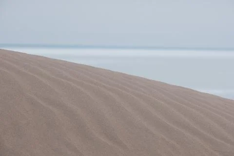 A sand dune with soft undulating patterns on the sand. In the background, you Foto stock