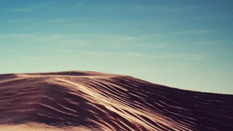 Sand dunes under a clear sky at sunset in a desert location Stock Footage 343499358