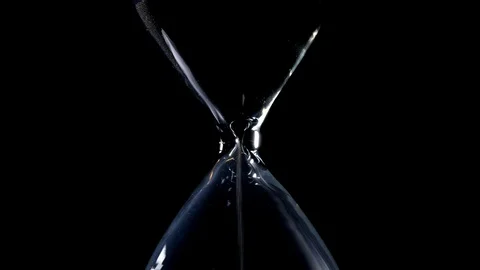 The sand flow in the centered hourglass with black background and backlight Stock Footage 90067952