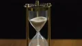 Sand flowing in golden hourglass on table, running time concept, minutes passing HD Footage