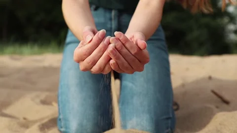 Sand is flowing thin stream through woman hands to the ground Stock-Footage 142375582