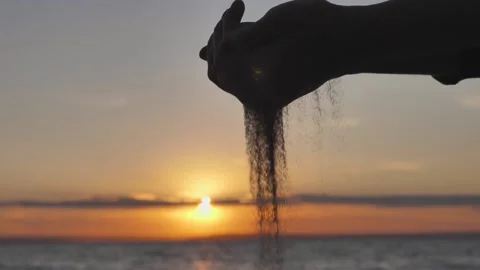 Sand Flowing Through Hands Against Sea Sunset. Concept of Transience Lifetime Stock Footage 136090367
