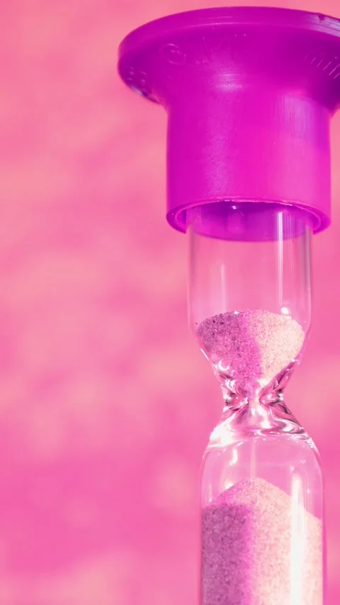 Sand flows from the top of an hourglass to the bottom while a purple lid sits on Stock Footage 331348121