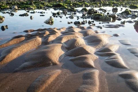 Sand formations and rocks on the beach in the evening light Foto stock