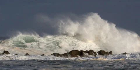Sand-laden foaming waves crashing over a narrow ridge of rock Stock Footage 59526715