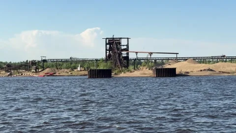 Sand mining equipment operating on the riverbank of a large river under dayli Stock Footage 310613209