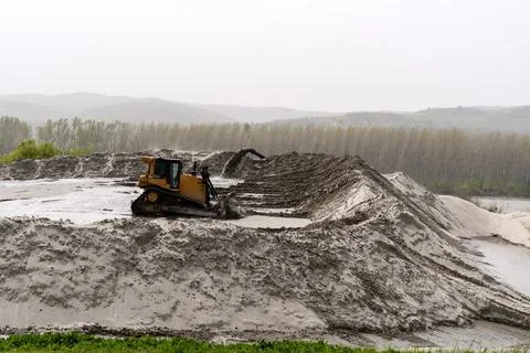 Sand mining industry. A mining bulldozer works on a huge pile of sand extract Stock Photos
