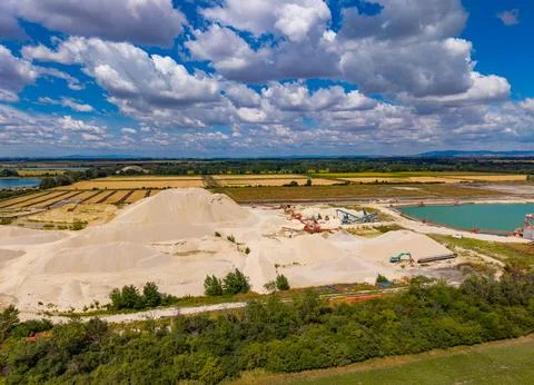 Sand mining operations take place near a river under a blue sky. Sand is be.. Stock Photos