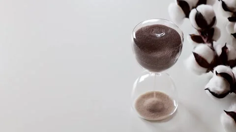 The sand passes through the bulbs of the hourglass standing on the table Stock-Footage 243499587