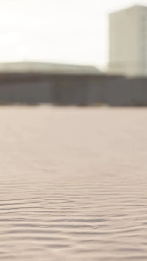 Sand patterns on beach with buildings in the background during sunny day Stock Footage 337942752