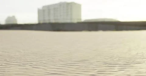 Sand patterns on a beach with buildings in the background at sunset Stock Illustration